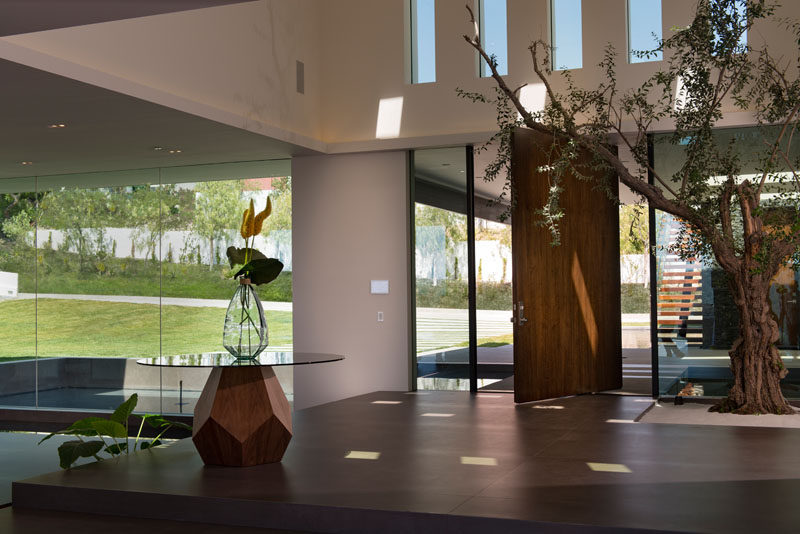 The large center-pivot front door opens to reveal the dramatic double-height foyer of this modern house. #PivotingDoor #Foyer 