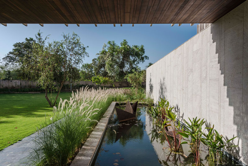 This modern house has a pond water feature that has a simple child-like sculpture of a folded sailboat. #WaterFeature #Landscaping #Garden