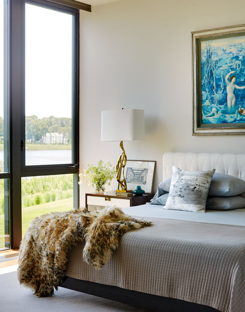 Large windows fill this contemporary bedroom with natural light and provide views of the harbor and cove in the distance. #Bedroom #BedroomIdeas #BedroomDesign