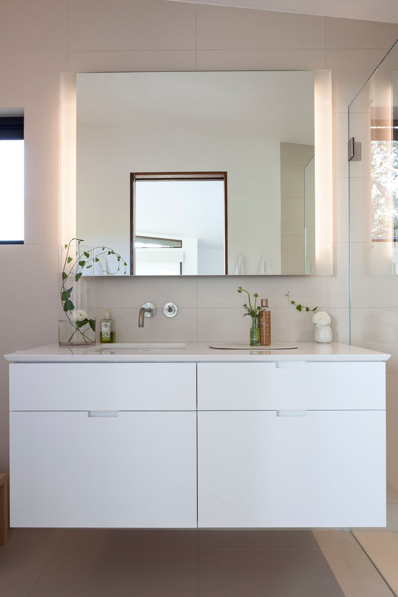 This contemporary bathroom has been kept bright with the use of light porcelain tiles and a white vanity. #BathroomDesign #Bathroom