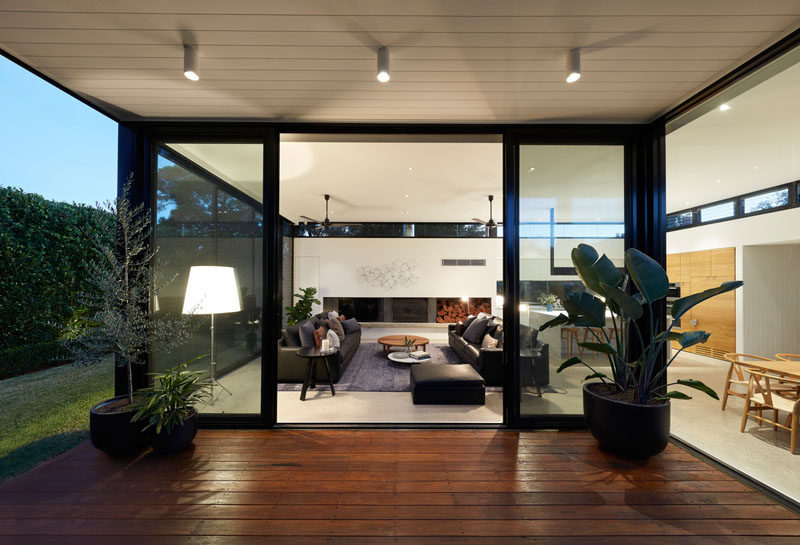 Sliding glass doors open this modern living room to a covered patio for outdoor dining. #Patio #LivingRoom #ModernHouse