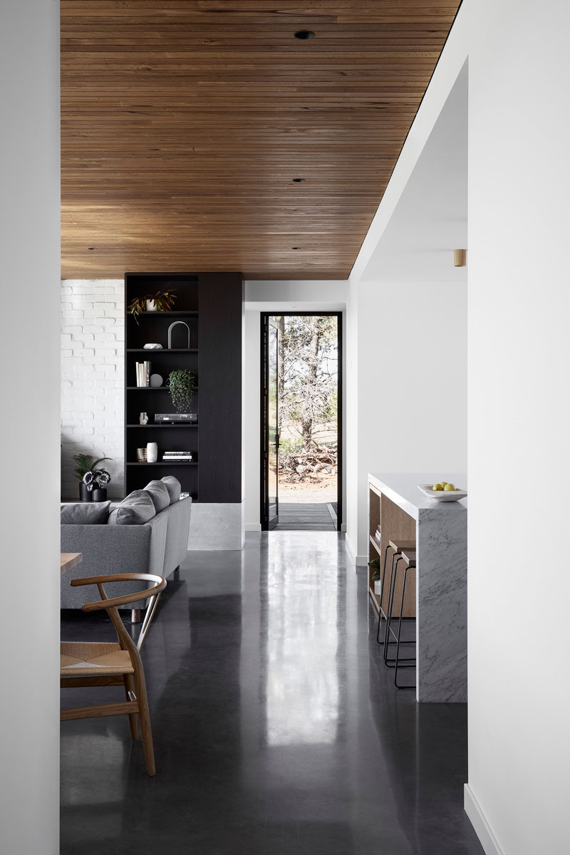 This modern house interior features a Blackbutt shiplap ceiling and burnished concrete flooring. #ConcreteFloor #DarkConcreteFloor #Flooring #WoodCeiling #Shiplap #ModernInterior