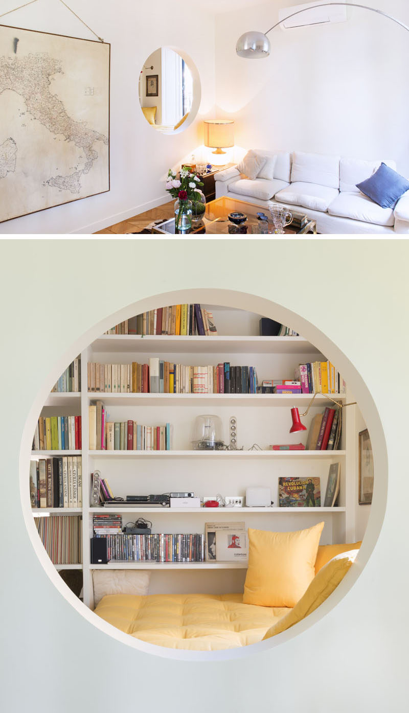 This modern home features an elevated reading nook that sits next to a window and a floor-to-ceiling bookshelf, and that has an opening that looks into the living room. #ReadingNook #InteriorDesign #CozyNook #Nook