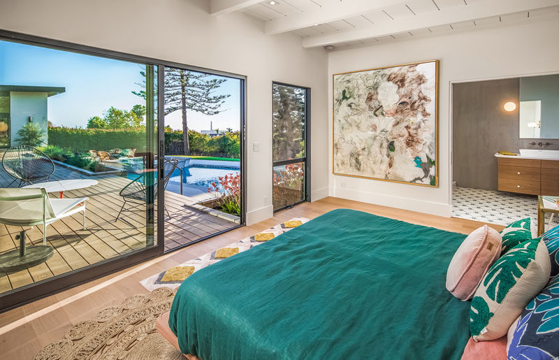 This modern master bedroom has a sliding door that opens to the deck and an ensuite bathroom.