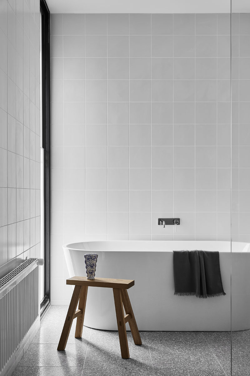 Square tiles have been used to cover the walls in this bathroom, while a freestanding white bathtub is positioned to take advantage of the views out of the window. #ModernBathroom #SquareTiles #FreestandingBathTub