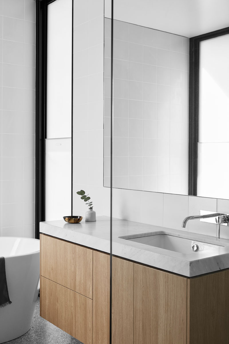 In this modern bathroom, a wood vanity adds a natural touch to the mostly white space. #ModernBathroom #WoodVanity