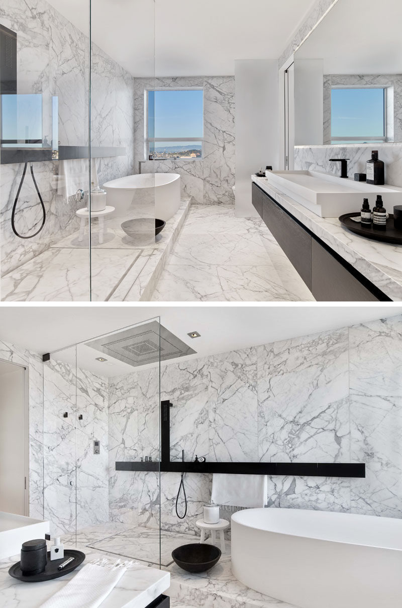 This modern master bathroom has floors and walls of carefully selected and matched Carrara marble slabs that are contrasted with dark fixtures to evoke the feeling of being in a spa. #ModernBathroom #MarbleBathroom #WhiteBathroom #InteriorDesign