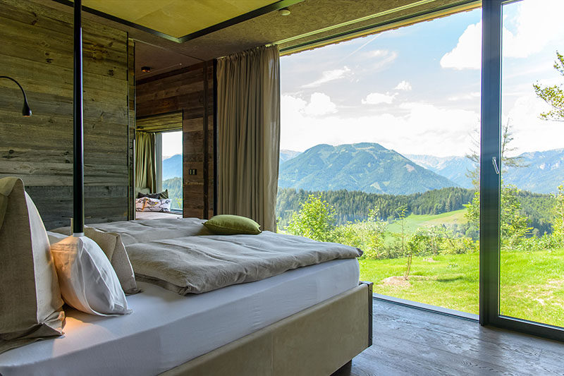 Panorama windows and recycled materials are featured in the bedroom of this modern mountain chalet. #Windows #RusticModern #WoodWall