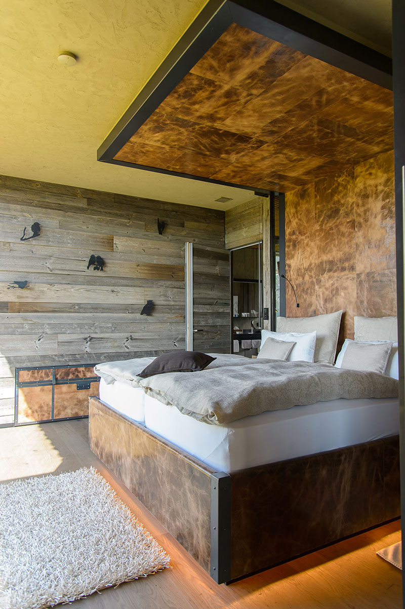 This modern mountain chalet has a bed frame wraps around the bed to become the headboard, that then continues onto the ceiling, creating a dramatic accent in the bedroom. #Bedroom #Bed #Headboard #Wood