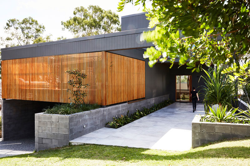 This modern black house has a wood slat detail that hides a private patio. #ModernHouse #ModernArchitecture