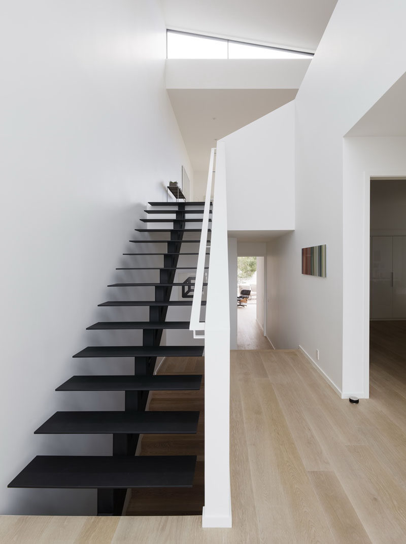 Minimalist black painted steel stairs lead to the upper floor of this modern house. #ModernStairs #BlackStairs