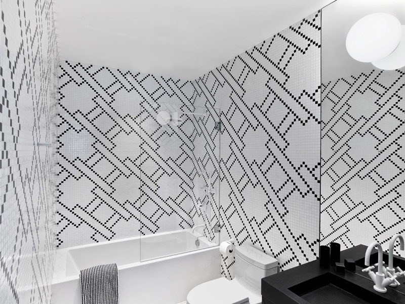 In this modern bathroom, the color palette has been kept simple by using black and white tiles, paired with a white bathtub and a black vanity. #BlackAndWhite #BathroomDesign #ModernBathroom #Pattern