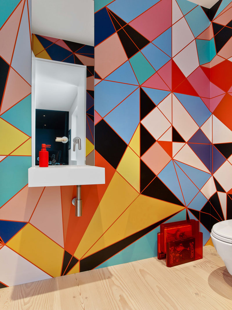 This modern bathroom has colorful and bold geometric pattern that covers the wall. #BrightBathroom #ColorfulBathroom #BathroomDesign