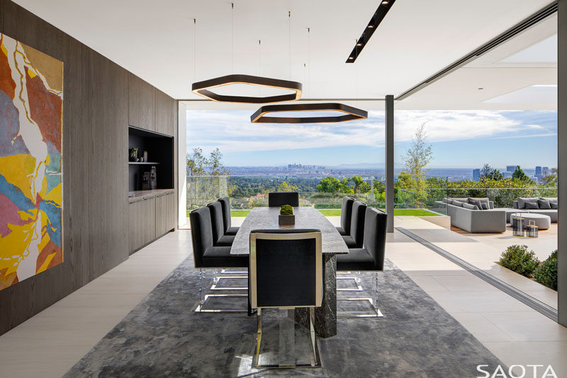 Where possible, walls in this renovated home were replaced by full height glazing with sliding windows, pocketing or stacking, to create generous openings, like in this dining room. #ModernDiningRoom #GlassWalls #InteriorDesign