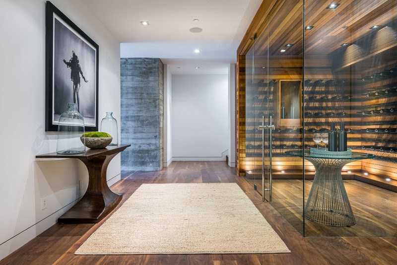 This modern house has a glass enclosed wine cellar with plenty of shelving and uplighting for showing off a wine collection. #WineCellar #WineStorage #InteriorDesign