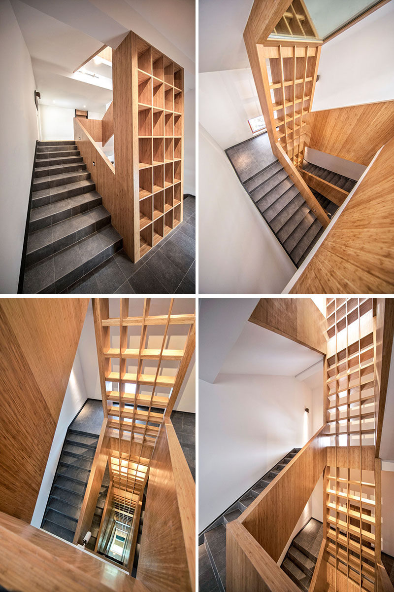 A staircase with stone tile, wood handrails and a large multi-floor wood bookshelf, connects the various levels of the hotel. #Stairs #Staircase #WoodBookshelf