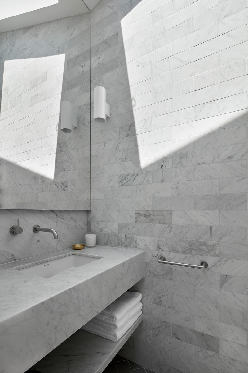 Floor-to-ceiling grey tiles have been installed in this new bathroom, and a skylight adds natural light to the room. #ModernBathroom #Skylight #BathroomDesign #GreyTiles