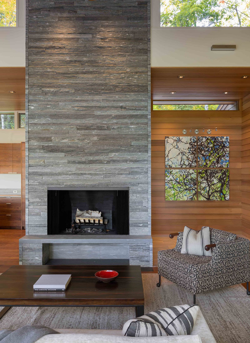 In this modern living room, there's a stacked stone fireplace and hearth, that draws the eye upwards to the clerestory windows and the height of the room. #Fireplace #StackedStoneFireplace #StoneFireplace #ModernFireplace