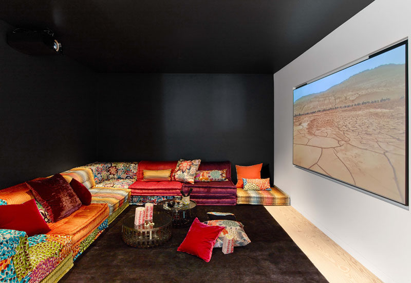 This modern house has a media lounge with black walls and a black ceiling, creating a cave-like atmosphere to enjoy the movie. #HomeTheater #MovieRoom