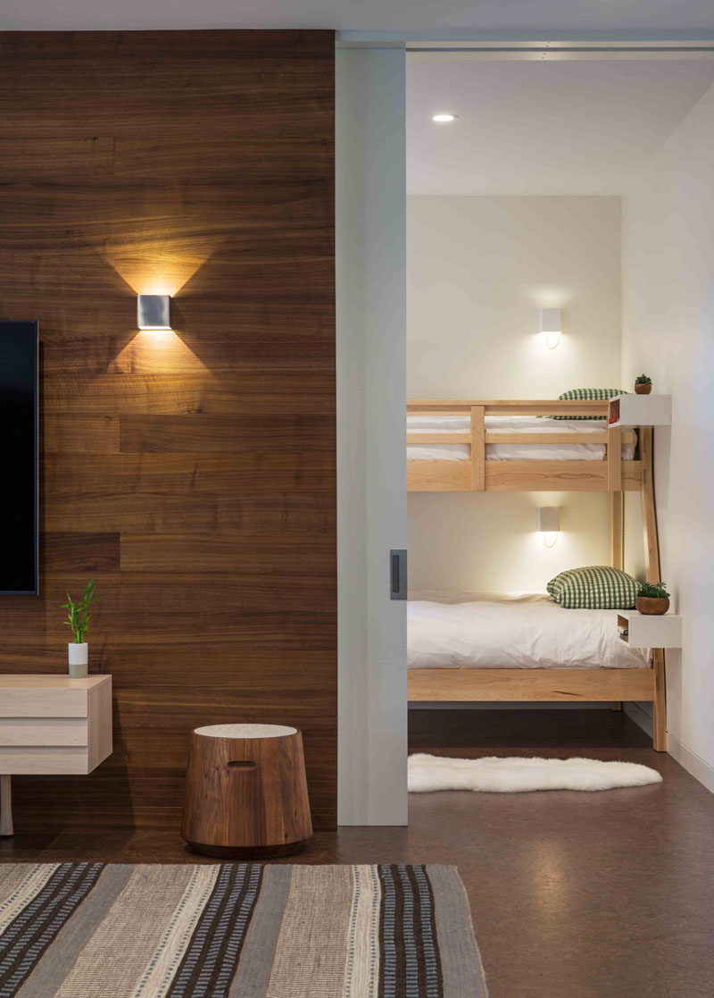 This modern house has a guest room with bunk beds that are located off a casual living room. #BunkBeds #PocketDoor #WoodAccentWall