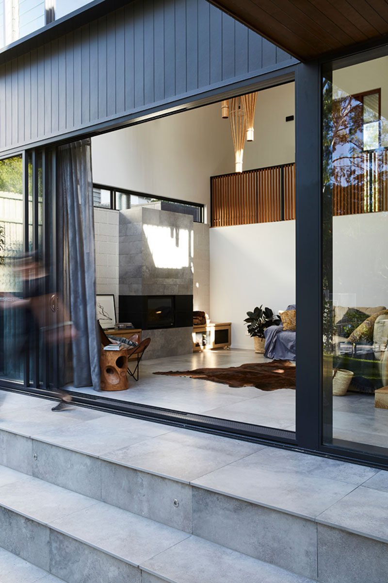 This modern living room, which is open to the backyard, has a stone fireplace and an abundance of natural light. #Fireplace #StoneFireplace #LivingRoom