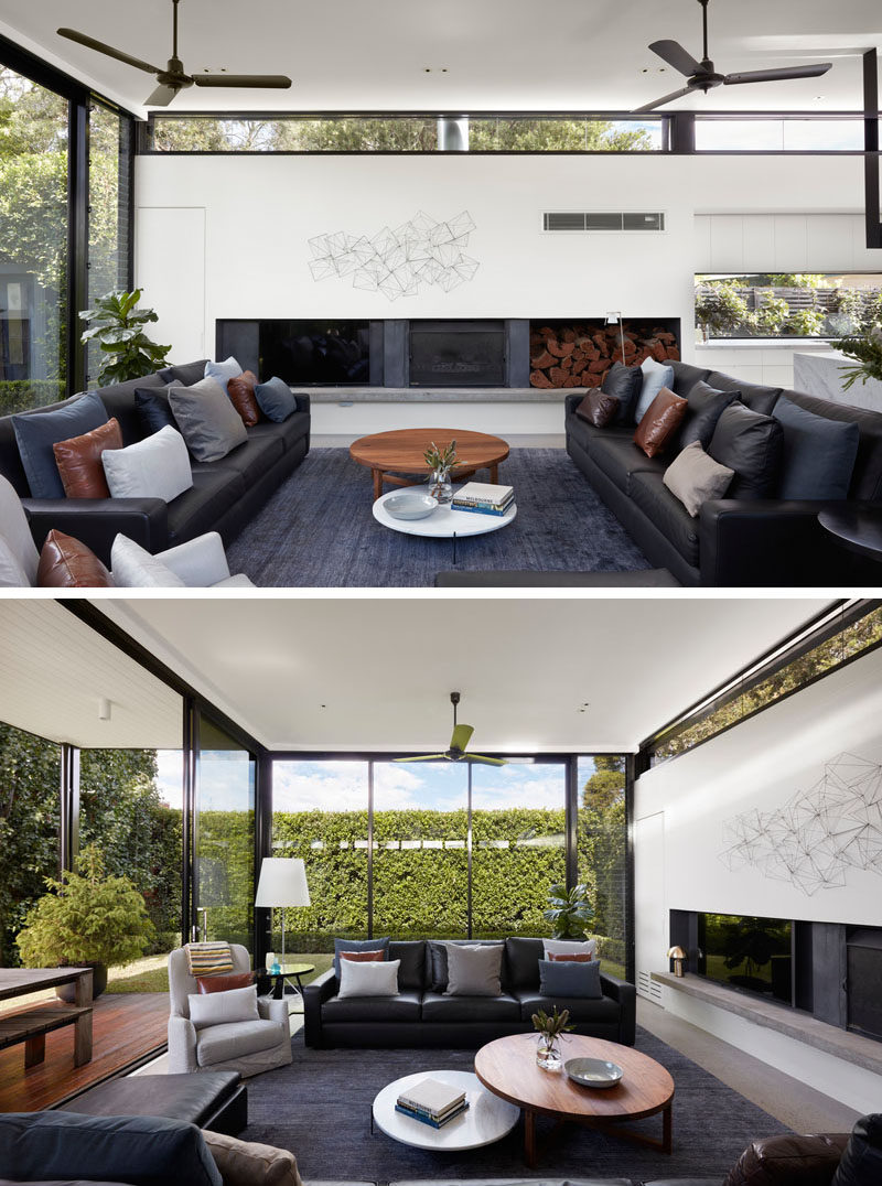 This modern living room has a fireplace and full height windows that provide views of the lush trees and greenery. #LivingRoom #ModernLivingRoom #Fireplace #Windows