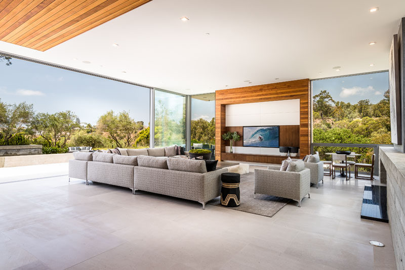 In this modern grand family room, there's plenty of seating, and large sliding glass walls open to the terrace. #GlassWalls #FamilyRoom #ModernLivingRoom