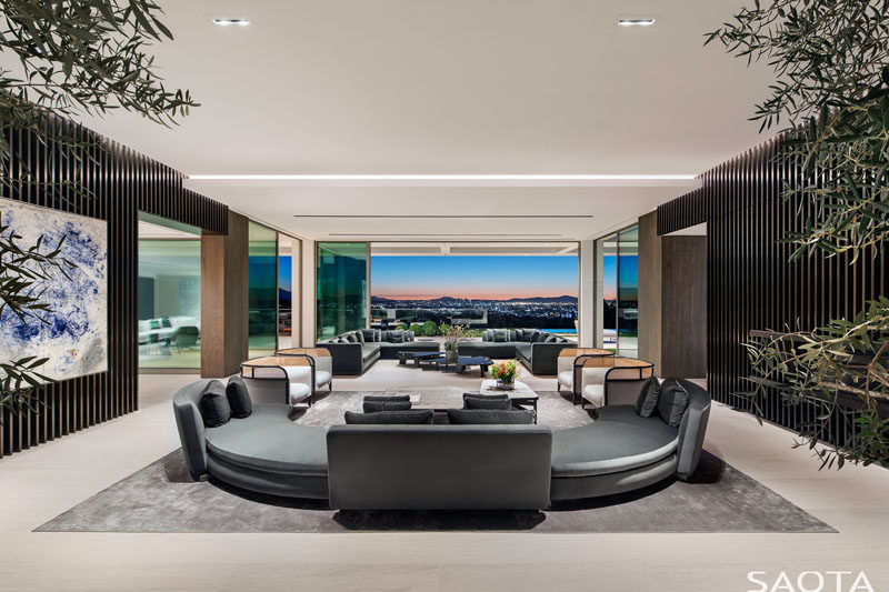 In this great room, there are two separate sitting areas that have been positioned to take advantage of the perfectly framed view. #CurvedCouch #GreatRoom #ModernLivingRoom