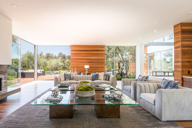 This modern house has a formal living room with a fireplace and floor-to-ceiling windows and glass doors that provide access to a terrace outside. #LivingRoom #InteriorDesign #ModernLivingRoom