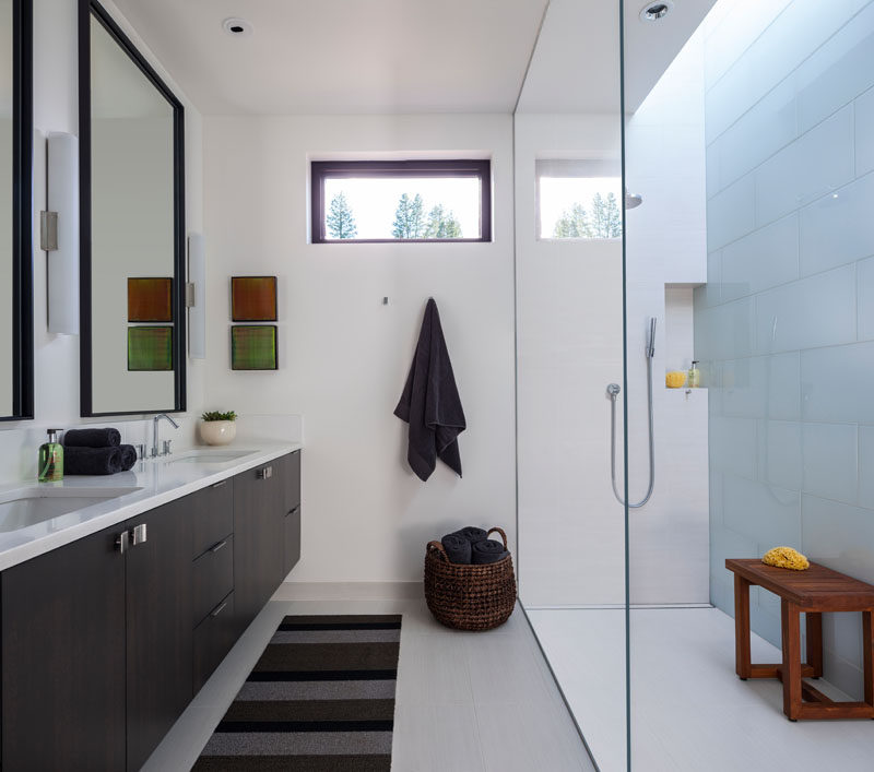 In this modern master bathroom, a skylight helps to keep the glass enclosed shower bright, while a dark vanity ties in with the rest of the dark wood used throughout the home. #MasterBathroom #ModernBathroom