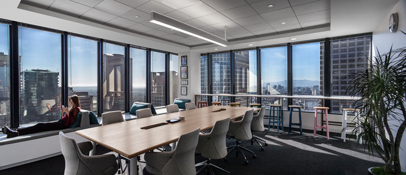 In this large meeting room, additional seating has been added in the form of window seats with backrests and a counter with stools. #OfficeDesign #ModernBoardroom #WindowSeats