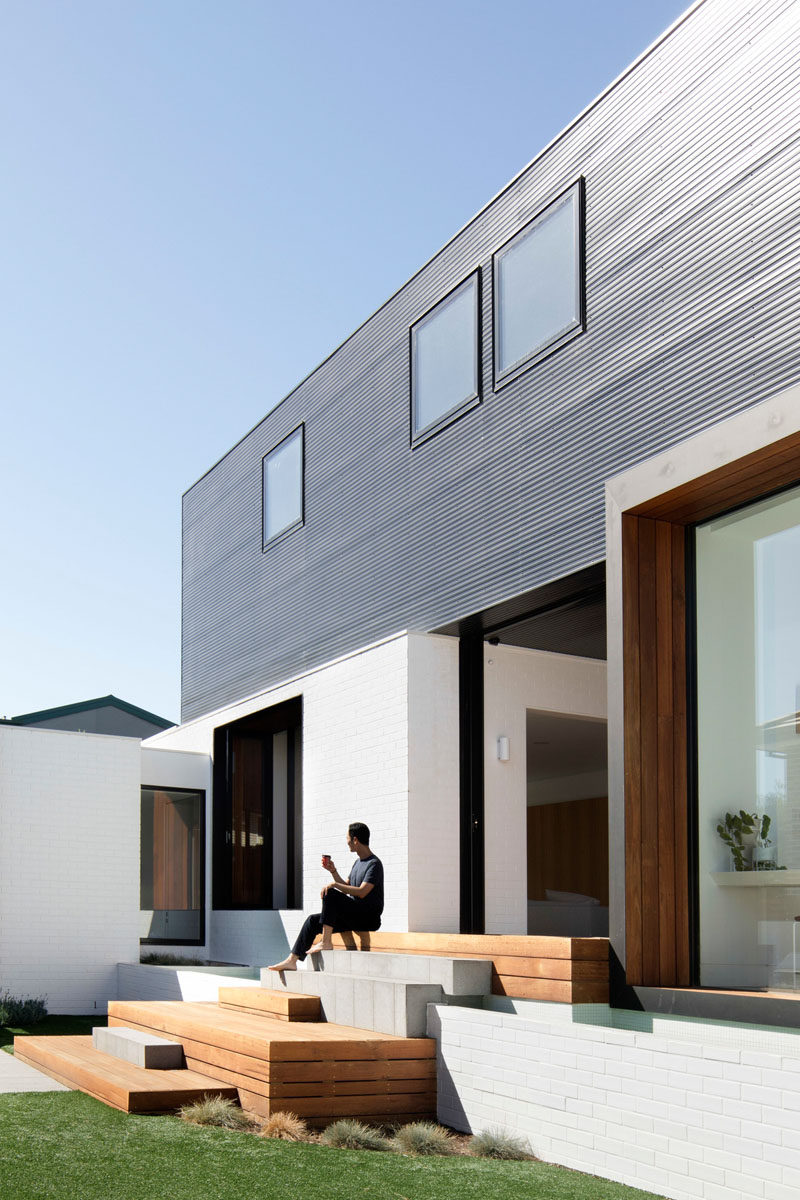 A mix of timber decking and paving steps, that double as seating, lead down to the backyard of this modern house. #OutdoorStairs #ExteriorStairs #Landscaping #Architecture