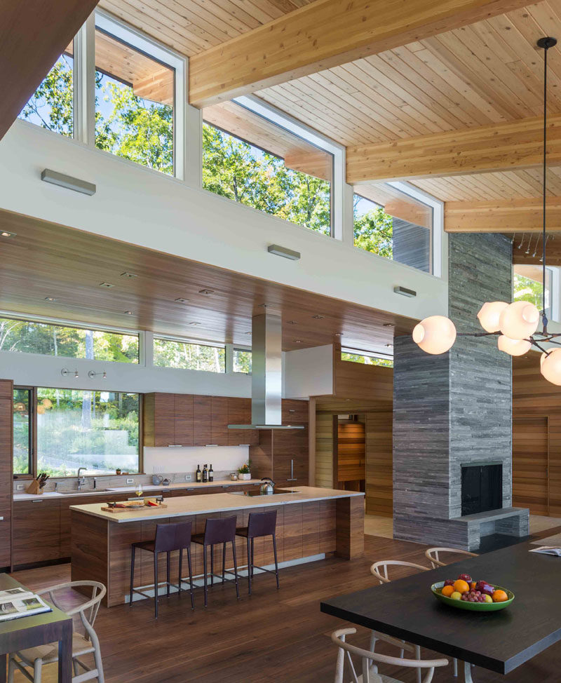 This modern kitchen has dark wood cabinets with white countertops, while a large island provides an additional place for seating. #ModernKitchen #WoodKitchen #KitchenDesign