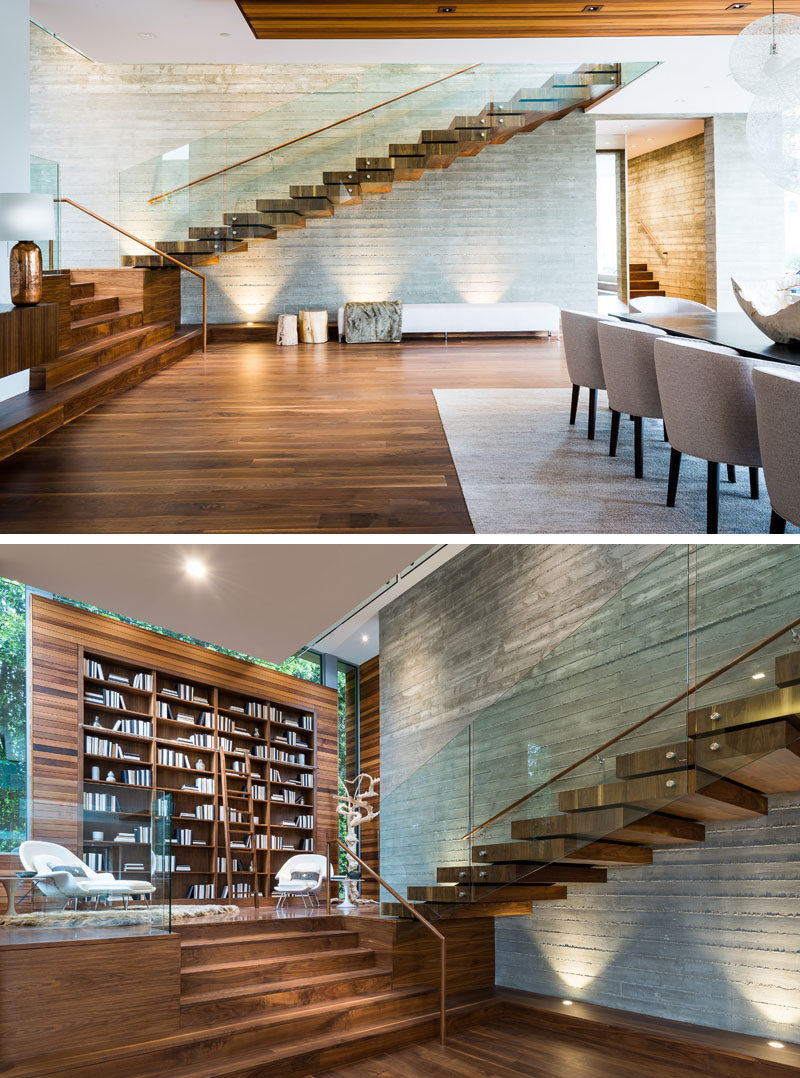 This modern wood and glass floating staircase has an enlarged landing that serves as a formal library with a 15-foot high built-in bookcase. #Library #HomeLibrary #Staircase #FloatingStairs #InteriorDesign #Bookcase