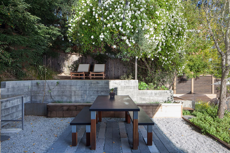 This modern backyard has several areas for relaxation, like the raised outdoor lounge area within the trees, and an outdoor dining patio. #ModernLandscaping #OutdoorDining #Garden #Backyard #LandscapeDesign