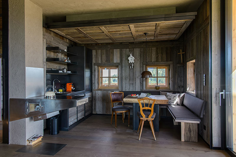 This rustic modern mountain chalet has a small kitchen with a fire place, and a corner dining area with banquette seating. #RusticModern #SmallKitchen #MountainChalet #BanquetteDining