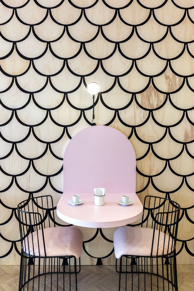 This modern patisserie features a graphic wood accent wall that features the u-shape, also known as a scalloped or fish scale pattern. The wall design wraps from the wall up onto the ceiling and over to the service area. #ModernCafe #Patisserie #InteriorDesign