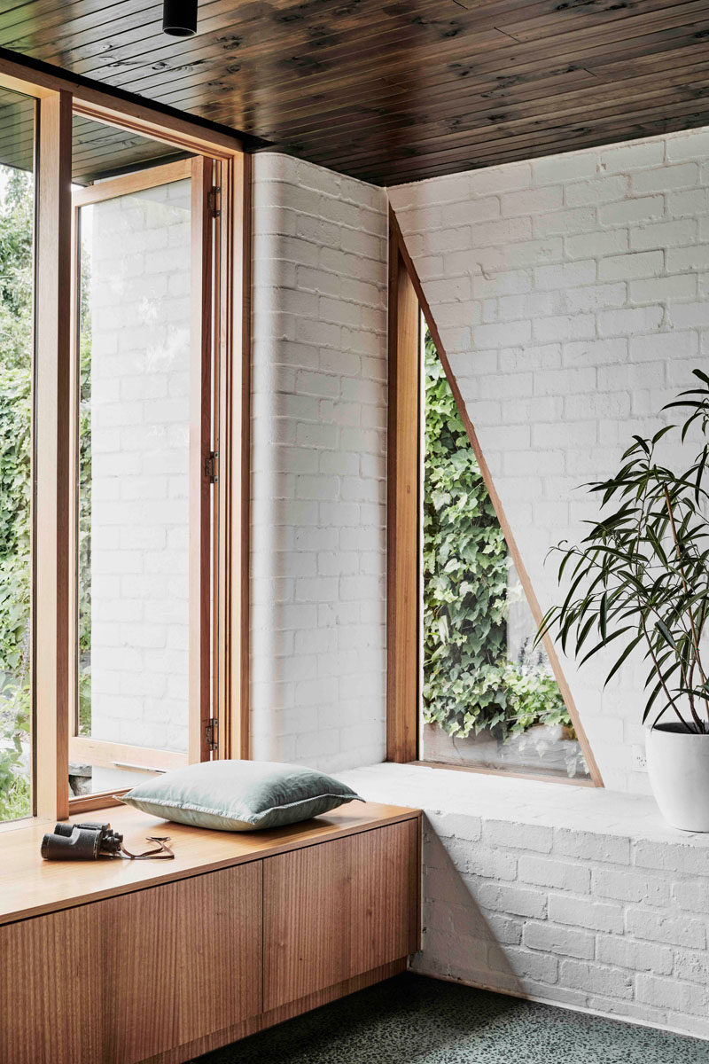 This modern interior features a white brick wall,wood cabinetry and a triangle window in the corner. #InteriorDesign #WhiteBrick #Window #TriangleWindow