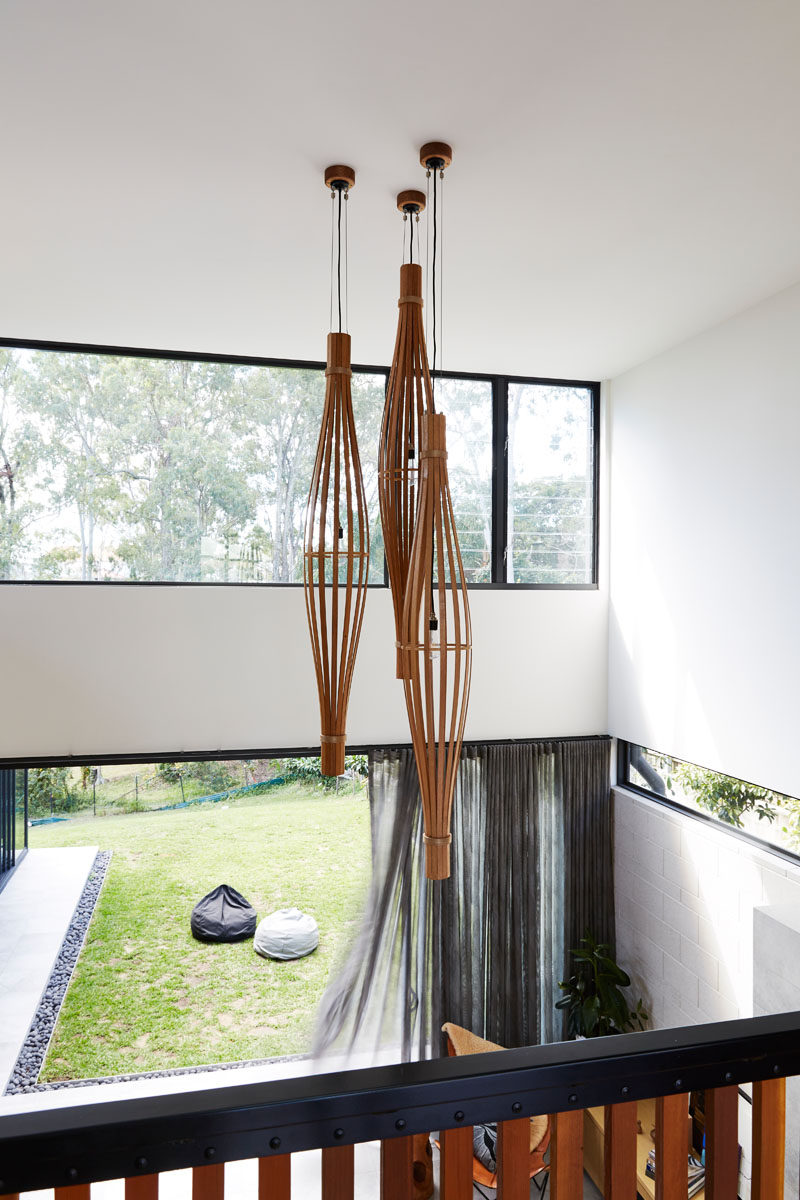 The entryway in this modern house overlooks the living room and backyard, and provides a view of the sculptural pendant lights. #Lighting #InteriorDesign