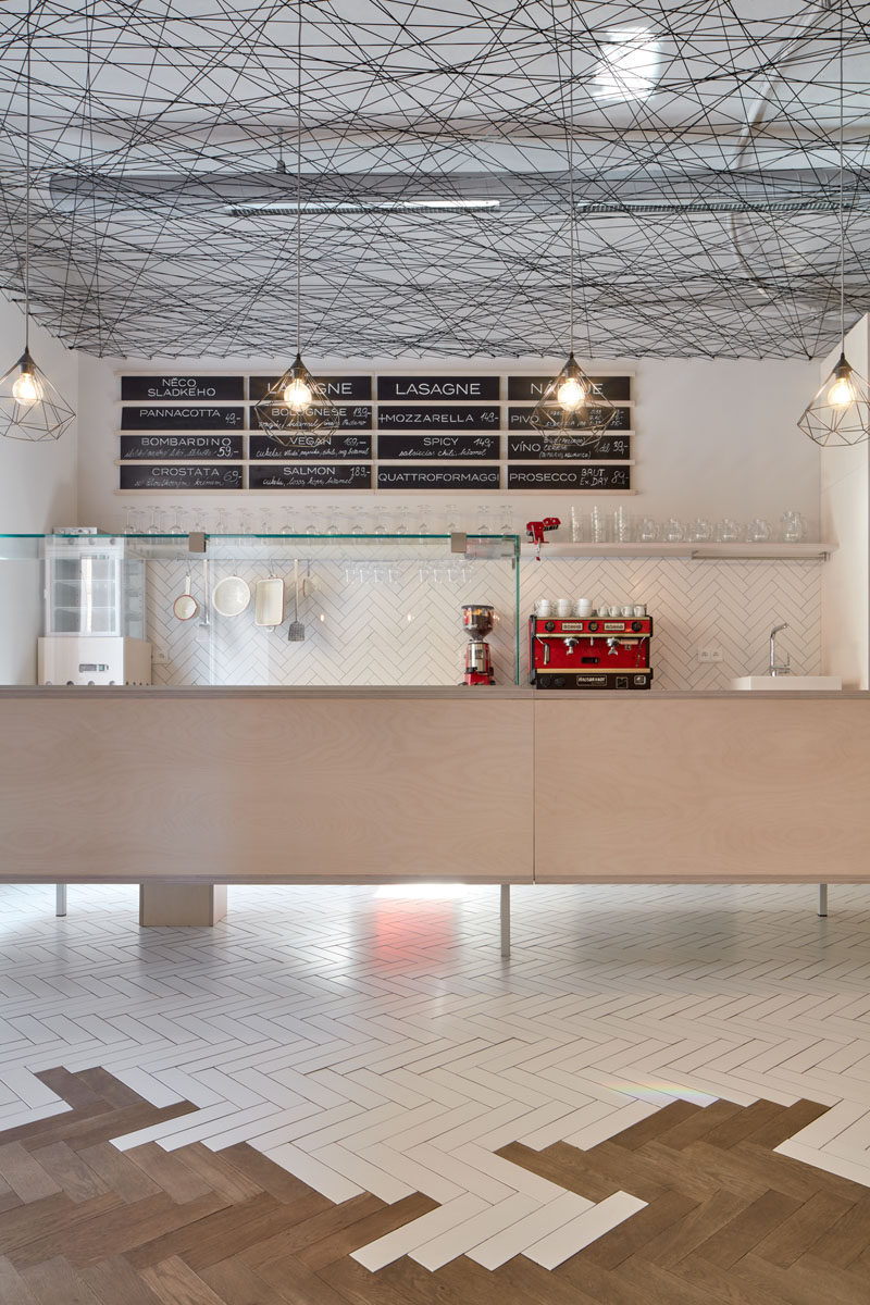 This modern bistro features a suspended web-like ceiling, and a wood and tile parquet floor. #ModernBistro #ModernRestaurant #InteriorDesign