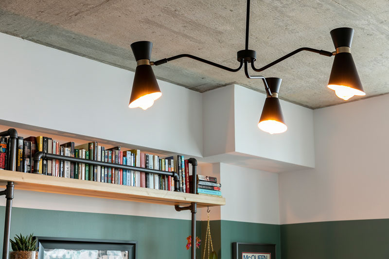 Francis Dominguez has transformed a spare empty bedroom into a library that features wood shelves, a metal ladder, and a reading area. #IndustrialModern #Library #InteriorDesign