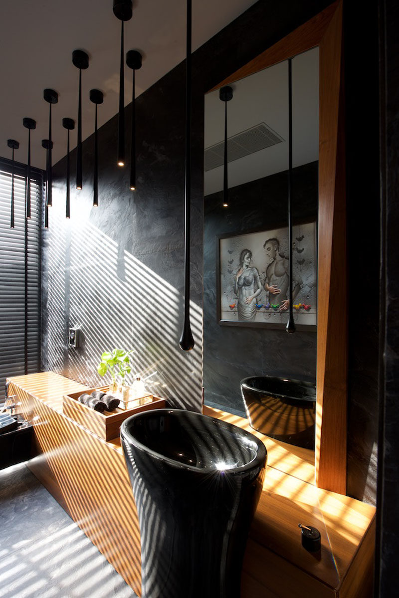 In this bathroom, black slate covers the walls and has been paired with rich wood for a modern and dramatic look. #ModernBathroom #BlackBathroom #BlackAndWoodBathroom