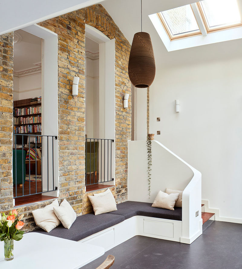 Inside this modern extension, there's elements of the original home on display, like the large brick wall, that provides a separation from the old and new areas of the home. A built-in bench provides a small sitting area in the extension. #BrickWall #Bench #SittingArea #InteriorDesign