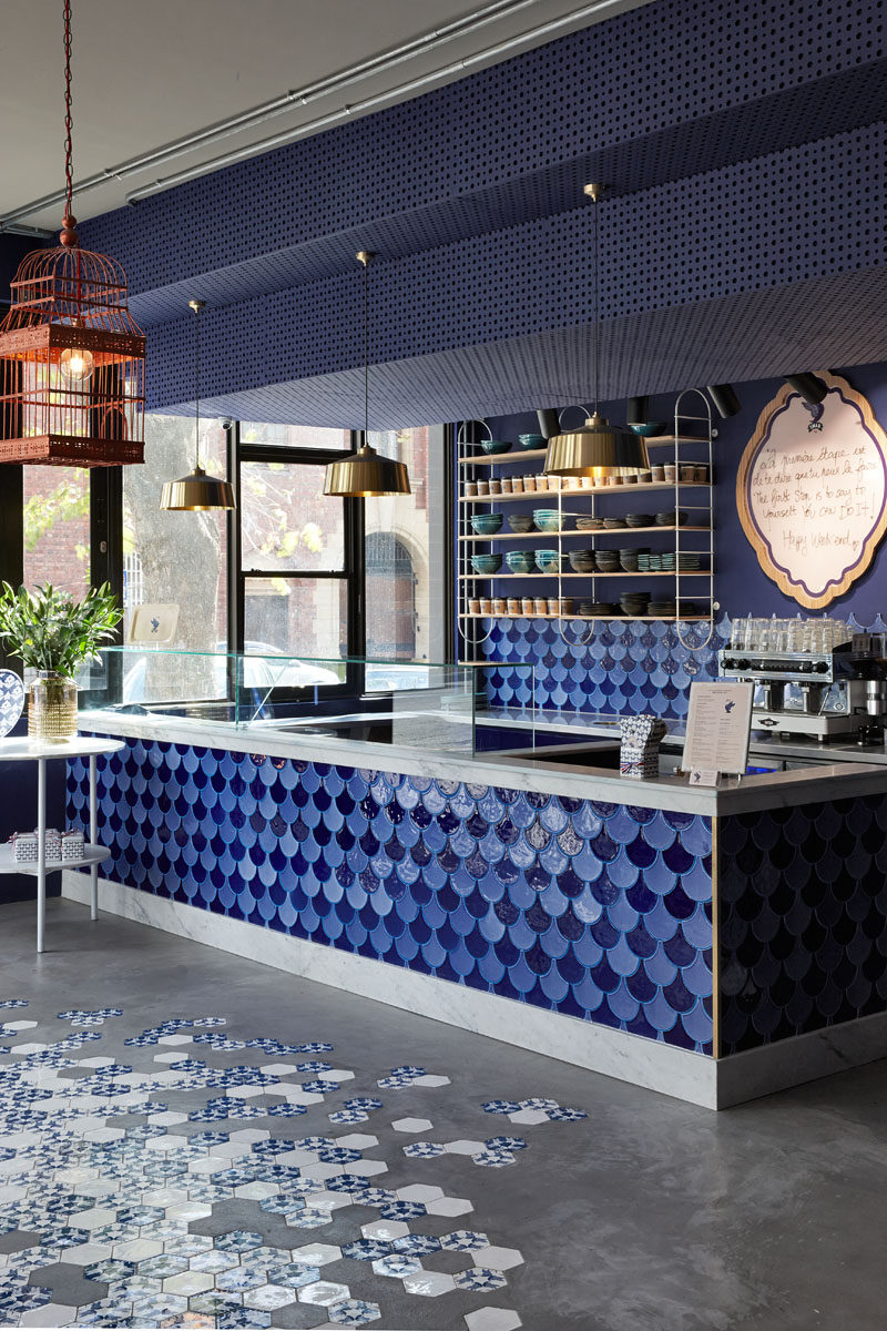  On the floor of this modern cafe, simple concrete screed flooring has been combined with custom blue and white hexagon tiles decorated with the cafe's logo. #ConcreteFloor #ConcreteAndTile #ModernFlooring