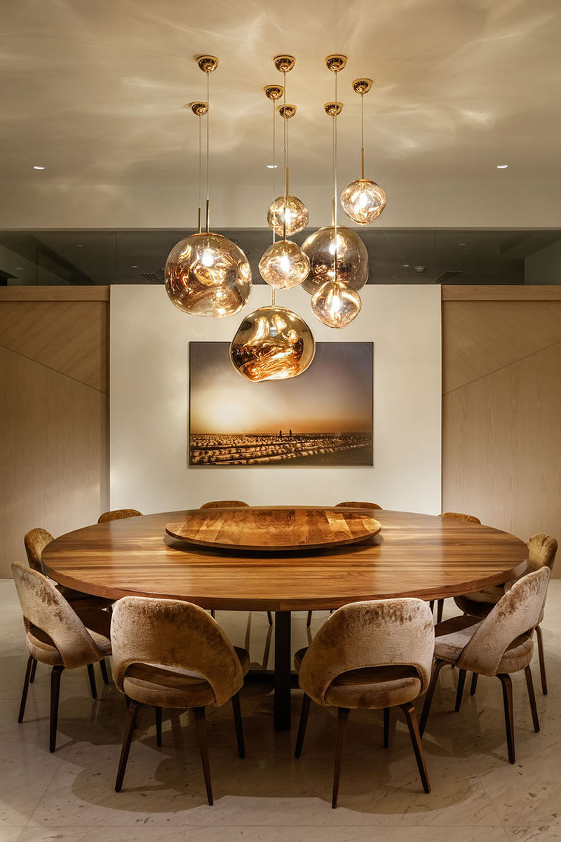 In this dining room, a collection of pendant lights hang above the large and round wood dining table. #DiningRoom #RoundDiningTable