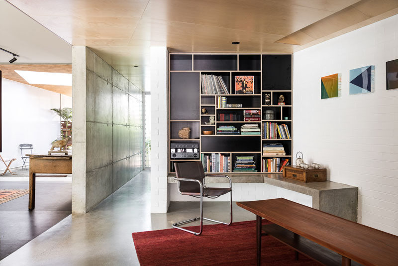 This modern house has a built-in black and wood bookshelf, and a concrete ledge. #Bookshelf #Shelving