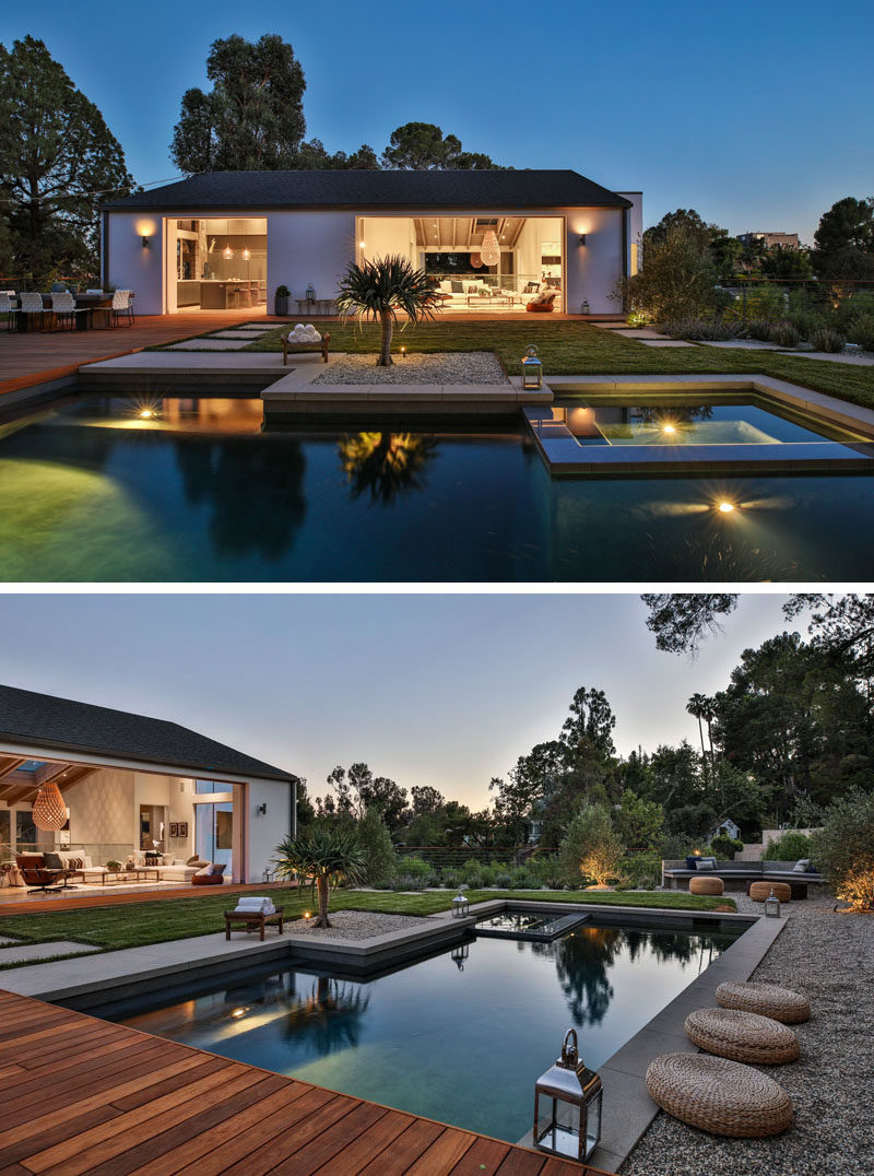 This landscaped backyard features a wood deck for outdoor dining and relaxing in the sun, a swimming pool surrounded by grass and pebbles, and a built-in outdoor lounge. #Landscaping #ModernBackyard #SwimmingPool #Deck