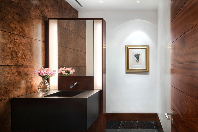 In this powder room, lighting has been used to highlight the artwork on the wall, and on either side of the mirror, soft lighting creates an ambient glow. #PowderRoom #Lighting