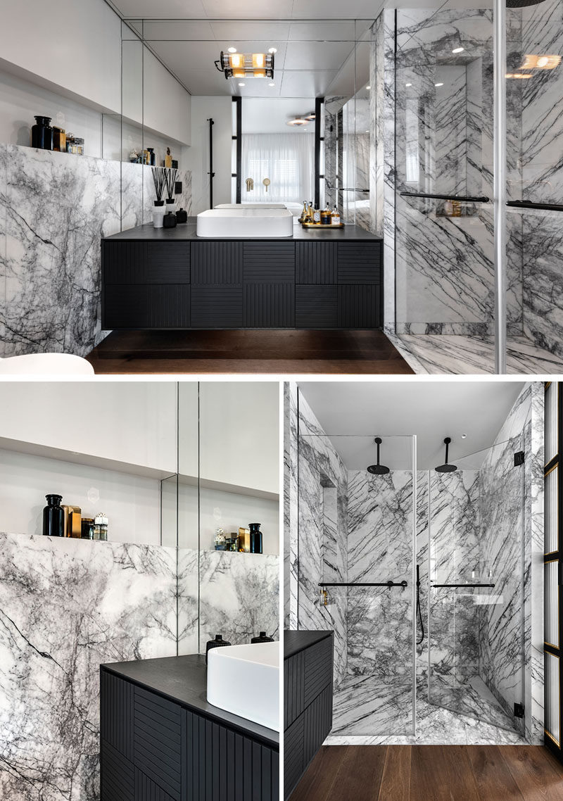 In this modern ensuite bathroom, a large mirror fills the wall, while a black vanity has a woven pattern featured on the front. Grey and white marble lines the two-person shower and the wall behind the toilet. #EnsuiteBathroom #BathroomDesign #ModernBathroom