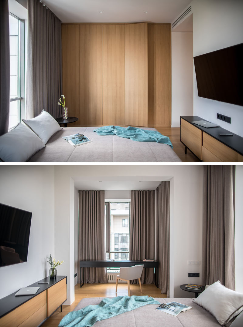 In this modern bedroom, there's a floor-to-ceiling wood closet, and a desk area that's been positioned in a small alcove by the windows. #BedroomDesign #ModernBedroom